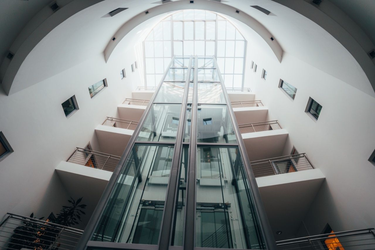 Lichtdurchflutetes Atrium mit gläsernen Aufzügen in einem Büro- und Geschäftshaus in Nürnberg