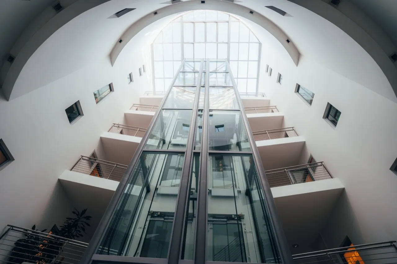 Lichtdurchflutetes Atrium mit gläsernen Aufzügen in einem Büro- und Geschäftshaus in Nürnberg